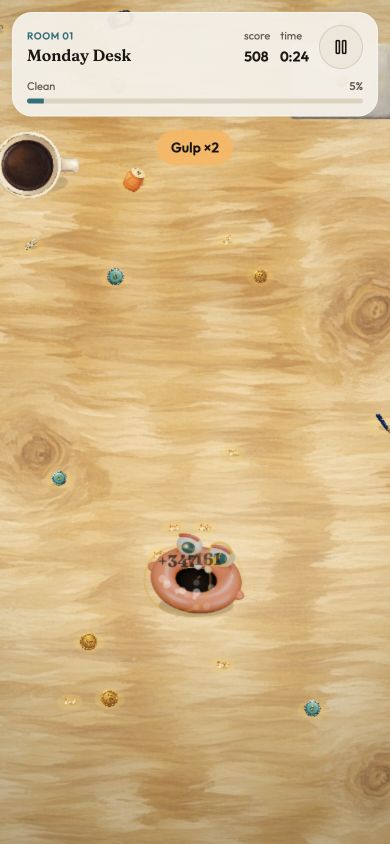 Actual GULP gameplay in Monday Desk, with the orange monster among crumbs, coins, pens and larger desk objects.